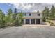 Three-car garage with modern doors and a spacious driveway with steps leading to the home's entrance at 30671 Bearcat Trl, Conifer, CO 80433