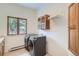 Clean laundry room with modern washer and dryer, storage cabinet, and natural light at 30671 Bearcat Trl, Conifer, CO 80433