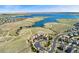 Aerial view showcases a beautiful home nestled near a tranquil lake, complemented by lush green spaces, pools, and scenic paths at 7051 S White Crow Way, Aurora, CO 80016