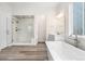 Well-appointed bathroom featuring a glass shower, soaking tub, modern vanity, and neutral tile flooring at 7051 S White Crow Way, Aurora, CO 80016