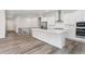 Modern kitchen with white cabinets, stainless steel appliances, island, and hardwood floors in a bright space at 7051 S White Crow Way, Aurora, CO 80016