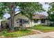 Charming home exterior with lush landscaping, lovely lawn, mature shade tree, and brick walkway to the front door at 334 S 7Th Ave, Brighton, CO 80601