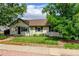 Home exterior displaying a manicured lawn, garden bed, mature shade trees, and a brick path to the front door at 334 S 7Th Ave, Brighton, CO 80601