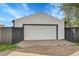 Detached garage with white siding and a large garage door surrounded by a privacy fence at 3064 S Galapago St, Englewood, CO 80110