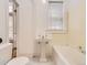 This is a simple bathroom featuring a pedestal sink, bathtub, white tile floor, and a window for natural light at 1453 Vine St, Denver, CO 80206