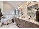 Modern bathroom with double vanity, oval mirrors, wood cabinets, soaking tub, and contemporary lighting at 2378 S Bannock St, Denver, CO 80223
