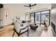 Bright living room with hardwood floors, a modern ceiling fan, and large windows overlooking the backyard at 2378 S Bannock St, Denver, CO 80223
