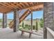 Covered back patio with stone columns, stairs to backyard, and seating area with landscaping at 9055 Swan River St, Littleton, CO 80125
