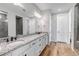 Bright bathroom boasts wood flooring, granite counters, white cabinets and large mirror at 9055 Swan River St, Littleton, CO 80125