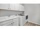 Modern laundry room with a utility sink, modern washer and dryer, and white cabinets for storage at 9055 Swan River St, Littleton, CO 80125