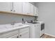 Bright laundry room with sink, white cabinets, and modern washer and dryer at 9055 Swan River St, Littleton, CO 80125