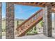 Wooden staircase leading to backyard, framed by stone pillars and featuring landscaped yard at 9055 Swan River St, Littleton, CO 80125