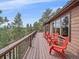 Spacious deck with multiple red chairs provides a scenic view of the surrounding evergreen trees at 11093 Milliken Ave, Conifer, CO 80433