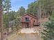 Back of house featuring multiple decks and a stone patio, nestled among mature trees at 11093 Milliken Ave, Conifer, CO 80433