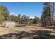 Large backyard with a greenhouse and trampoline, surrounded by mature trees on a sunny day at 7596 Rafter Rd, Franktown, CO 80116