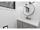 Modern half-bathroom with a round mirror, gray vanity, and contemporary fixtures at 7596 Rafter Rd, Franktown, CO 80116