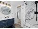 Modern bathroom features a vanity, round mirror, and a luxurious shower with decorative marble tiling at 7596 Rafter Rd, Franktown, CO 80116