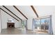 Open living area with fireplace, wooden beams, and sliding glass doors to a spacious deck at 7596 Rafter Rd, Franktown, CO 80116