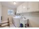 Well-lit laundry room featuring a washer, dryer, utility sink, and storage cabinets at 6227 Colorow Dr, Morrison, CO 80465