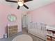 Charming bedroom with pink walls, a changing table, a crib, and a circle rug at 17411 E Layton Dr, Aurora, CO 80015