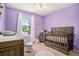 A delightful Bedroom is bathed in soft lavender, with a cozy crib and window seat at 5310 E Manchester Dr, Castle Rock, CO 80104