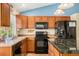 Well-equipped kitchen featuring dark appliances, wooden cabinetry, and a tiled backsplash at 5310 E Manchester Dr, Castle Rock, CO 80104