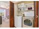 A laundry room features newer washer, dryer and wooden slat door to the purple bedroom at 5310 E Manchester Dr, Castle Rock, CO 80104