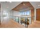 A well-lit hallway showcases modern design, with a glass railing and views into the living spaces below at 651 Emberglow Ln, Highlands Ranch, CO 80126