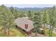 Birds-eye view of a wooded property, home, and deck, surrounded by tall pine trees at 29857 Park Village Dr, Evergreen, CO 80439