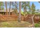 Backyard fenced in with stairs to the deck, grassy area and mature trees at 29857 Park Village Dr, Evergreen, CO 80439
