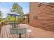 Wooden deck featuring metal table and chair set, blue umbrella and wood fencing at 29857 Park Village Dr, Evergreen, CO 80439
