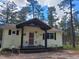 Charming cottage-style home with a welcoming front porch and beautifully maintained landscaping surrounded by mature trees at 36351 County Road 21, Elizabeth, CO 80107