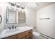 Bathroom featuring modern vanity, updated mirror and light fixture, and tiled shower at 7077 Ammons St, Arvada, CO 80004