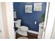 Charming half bathroom featuring blue walls, artwork, a white toilet and small decorative plant at 2147 N Downing St, Denver, CO 80205