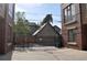 Backyard view of brick townhomes with secure black metal gate, detached garage, and some trees at 2147 N Downing St, Denver, CO 80205