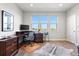 Home office with hardwood floors, a dark wood desk with computer, three large windows and a decorative hide at 7950 Piney River Ave, Littleton, CO 80125