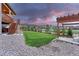Backyard with a stone patio, pergola, manicured lawn and fence. Stairs lead to a deck at 6470 Amur Ct, Castle Rock, CO 80108