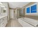 A bright bathroom featuring a glass shower, soaking tub, and neutral tile flooring at 6470 Amur Ct, Castle Rock, CO 80108
