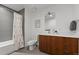 Well-lit bathroom featuring wood vanity, shower with patterned curtain, toilet, and light gray tiled floor at 3233 Tejon St # 305, Denver, CO 80211