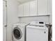 Bright laundry room with white cabinetry and modern washer and dryer units at 9471 Crossland Way, Highlands Ranch, CO 80130