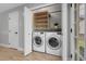 Laundry room featuring modern washer and dryer units, wood shelving, and ample storage at 11757 W Tufts Pl, Morrison, CO 80465