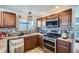 Well-lit kitchen featuring stainless steel appliances, wood cabinetry, and tile backsplash at 5251 Altura St, Denver, CO 80239