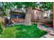 Landscaped backyard with a large tree, patio, and raised garden beds at 1563 High St, Denver, CO 80218