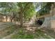 Spacious backyard with mature trees, wooden retaining wall, and partial fencing, perfect for outdoor activities at 2366 S Troy St, Aurora, CO 80014