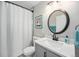 Updated bathroom with a stylish round mirror, gray cabinets, and white shower curtain at 1892 S Meade St, Denver, CO 80219
