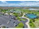 Aerial view of a clubhouse with tennis courts, parking, and a lake and mountain views in the background at 14879 Xenia St, Thornton, CO 80602