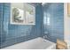 Bright bathroom with a shower over bath and blue tiled walls at 5557 Aspen Ave, Erie, CO 80516