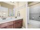 Well lit bathroom featuring double vanity, tiled shower-tub combo and sleek fixtures at 19814 Lindenmere Dr, Monument, CO 80132