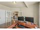 A bright home office features a large wooden desk and double French doors for ample sunlight at 19814 Lindenmere Dr, Monument, CO 80132