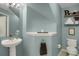 Bathroom featuring a pedestal sink, toilet, shelves, and a light blue wall color at 6476 Silver Mesa Dr # A, Highlands Ranch, CO 80130